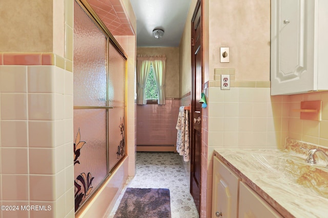 bathroom with vanity, tile walls, a baseboard heating unit, and enclosed tub / shower combo