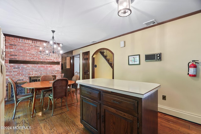 kitchen with dark hardwood / wood-style flooring, ornamental molding, decorative light fixtures, a notable chandelier, and a center island