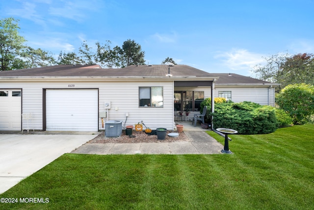 rear view of property featuring a garage, central AC, and a yard