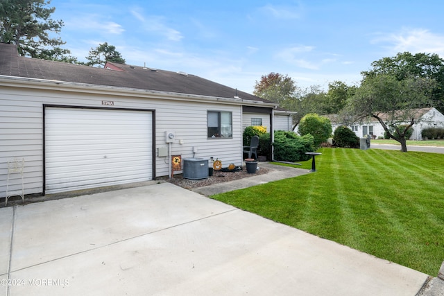 exterior space featuring a garage, a lawn, and central air condition unit