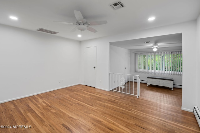 spare room with wood-type flooring, ceiling fan, and a baseboard radiator