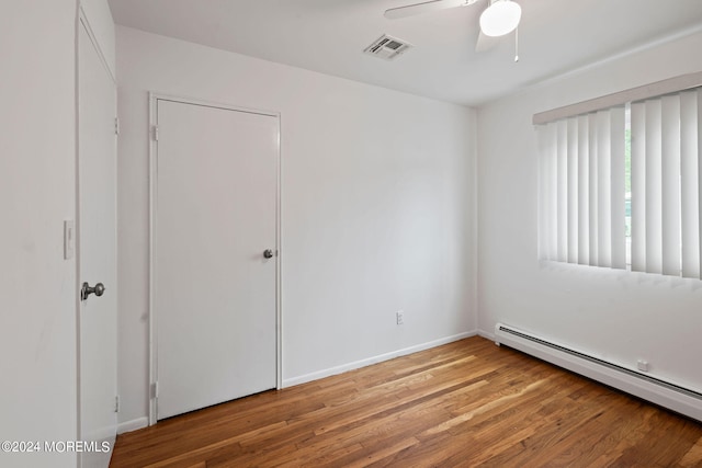 unfurnished bedroom featuring wood-type flooring, ceiling fan, and baseboard heating