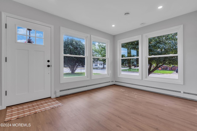 foyer entrance featuring a baseboard heating unit and light wood-type flooring