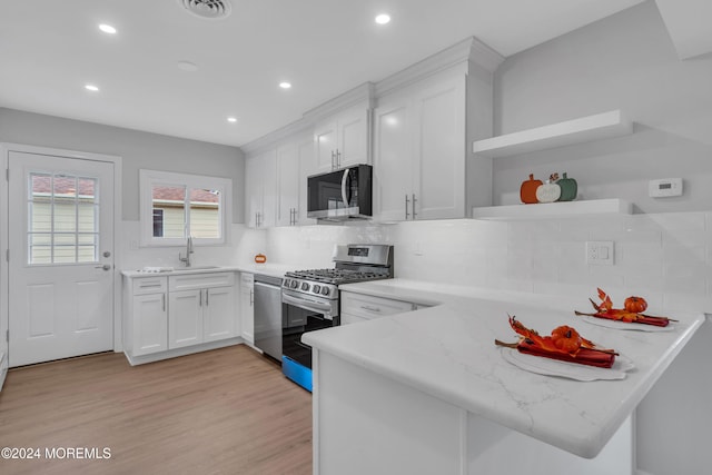 kitchen featuring light stone counters, kitchen peninsula, light hardwood / wood-style flooring, white cabinetry, and stainless steel appliances