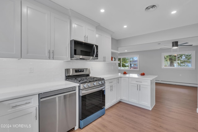 kitchen with stainless steel appliances, kitchen peninsula, light wood-type flooring, and white cabinetry