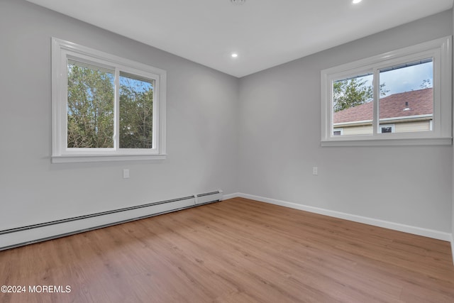 empty room with plenty of natural light, a baseboard radiator, and light hardwood / wood-style flooring