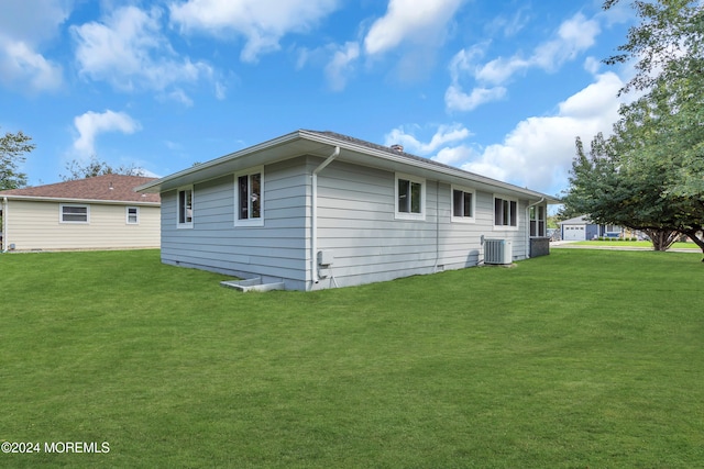 rear view of house with central AC and a lawn