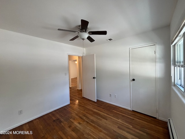 unfurnished bedroom with a baseboard radiator, ceiling fan, and dark wood-type flooring