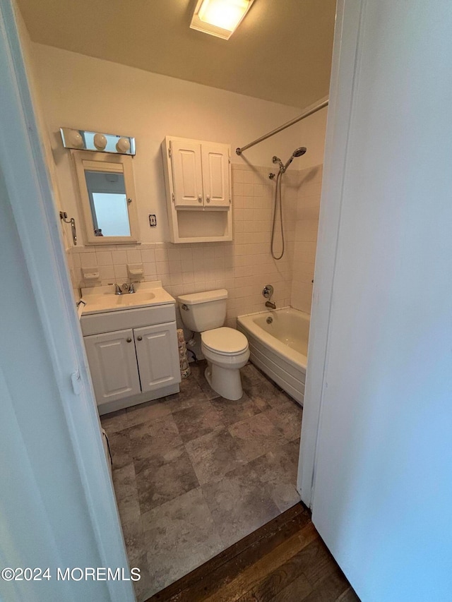 full bathroom featuring vanity, toilet, tiled shower / bath combo, tile walls, and hardwood / wood-style floors