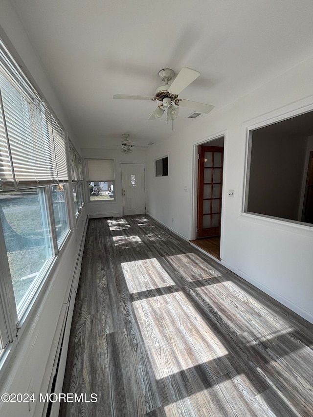 spare room with a wealth of natural light, ceiling fan, and dark wood-type flooring