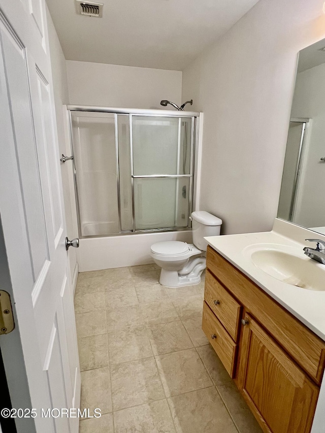 full bathroom with visible vents, vanity, tile patterned floors, combined bath / shower with glass door, and toilet