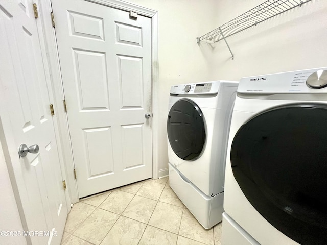 clothes washing area featuring laundry area, light tile patterned floors, and washing machine and clothes dryer