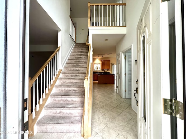 stairway with baseboards and a towering ceiling