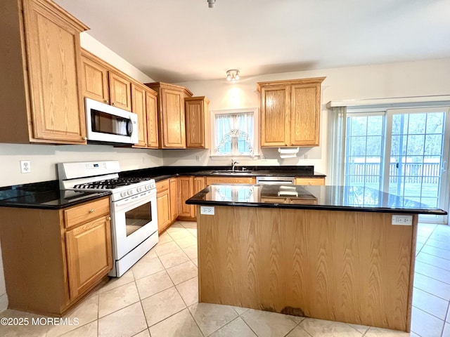 kitchen featuring plenty of natural light, a sink, light tile patterned floors, and white appliances