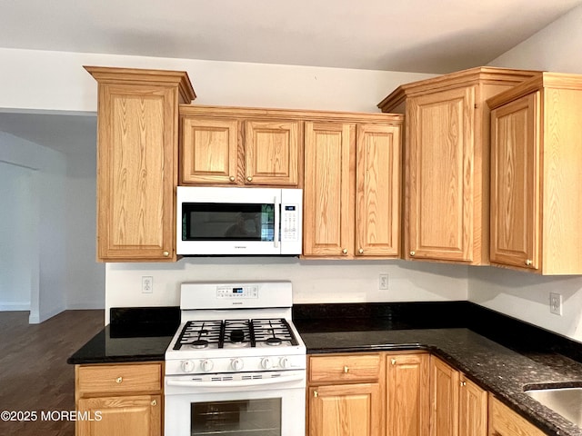 kitchen featuring dark stone counters, dark wood-style flooring, and white appliances