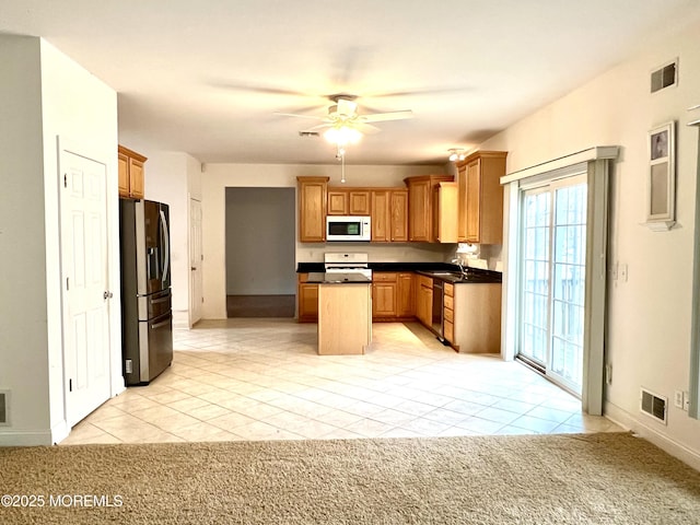 kitchen with stove, black dishwasher, white microwave, stainless steel refrigerator with ice dispenser, and visible vents