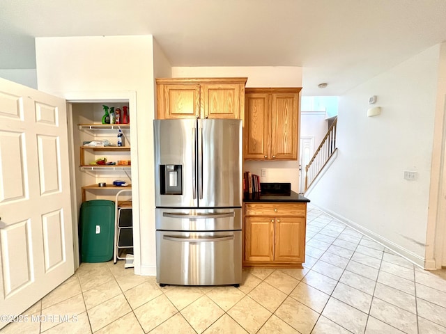 kitchen with stainless steel fridge, light tile patterned floors, and dark countertops