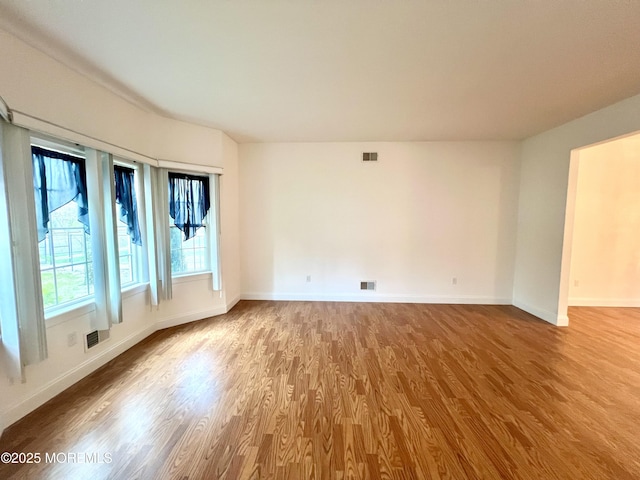 spare room with baseboards, visible vents, and wood finished floors