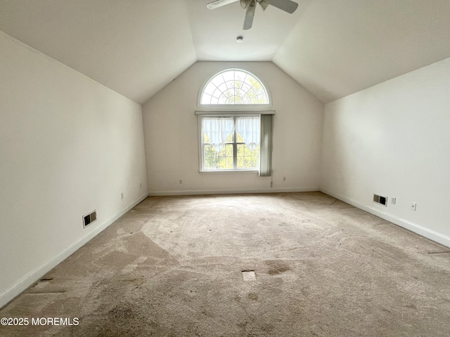 interior space featuring carpet flooring, a ceiling fan, visible vents, and vaulted ceiling