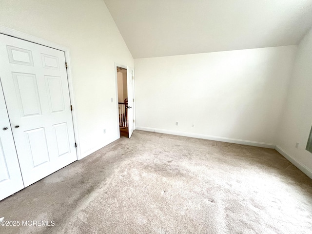 unfurnished bedroom with baseboards, carpet, and vaulted ceiling
