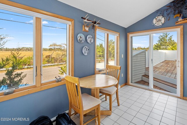 dining space with lofted ceiling, light tile patterned floors, and a healthy amount of sunlight