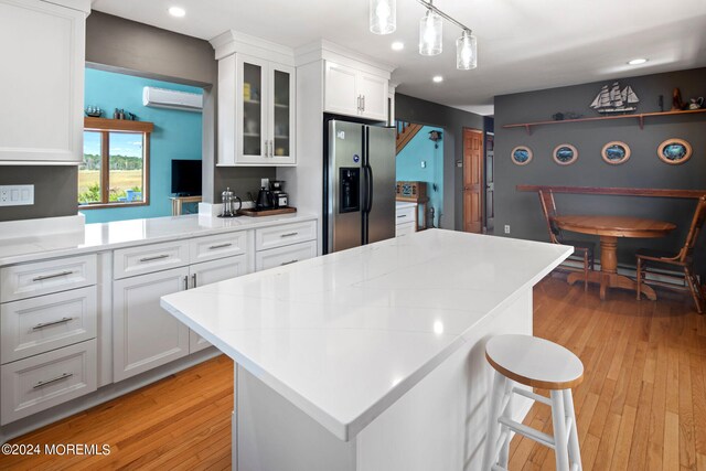 kitchen featuring decorative light fixtures, white cabinetry, stainless steel fridge with ice dispenser, and light hardwood / wood-style flooring