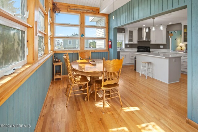 dining area with wooden walls, light wood-type flooring, and sink