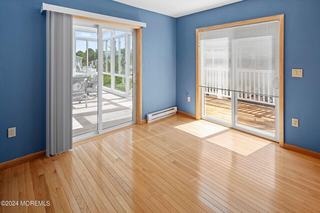 empty room featuring a baseboard radiator and light wood-type flooring