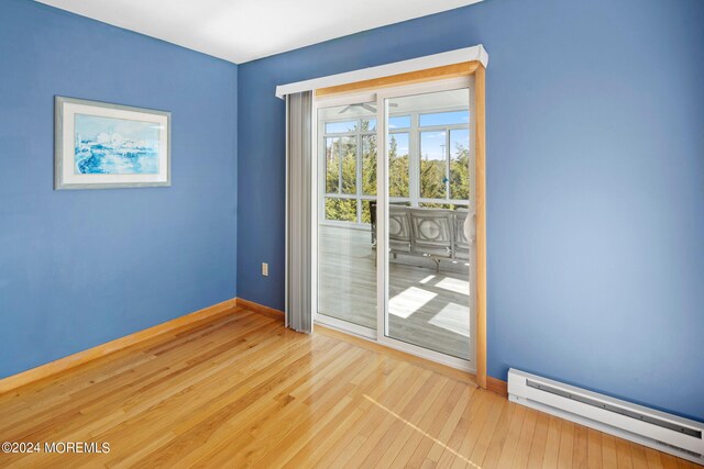 spare room featuring a baseboard heating unit and hardwood / wood-style flooring