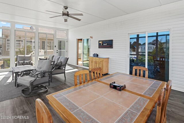 dining room with wood walls, dark hardwood / wood-style flooring, and ceiling fan