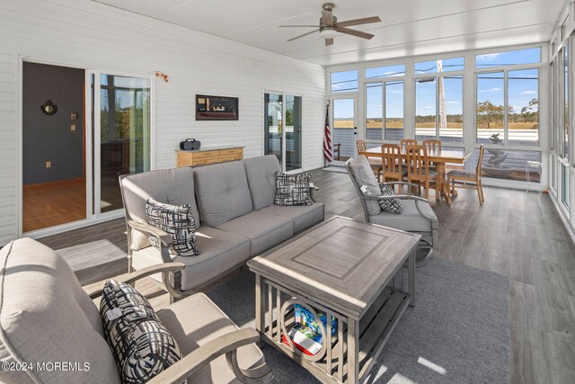 sunroom / solarium featuring a water view and ceiling fan