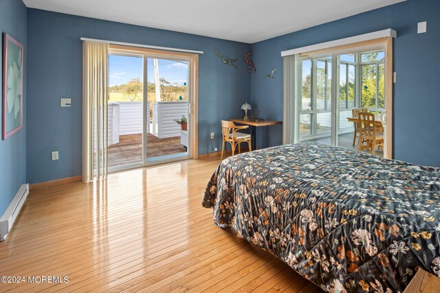 bedroom featuring a baseboard radiator, light wood-type flooring, and access to outside