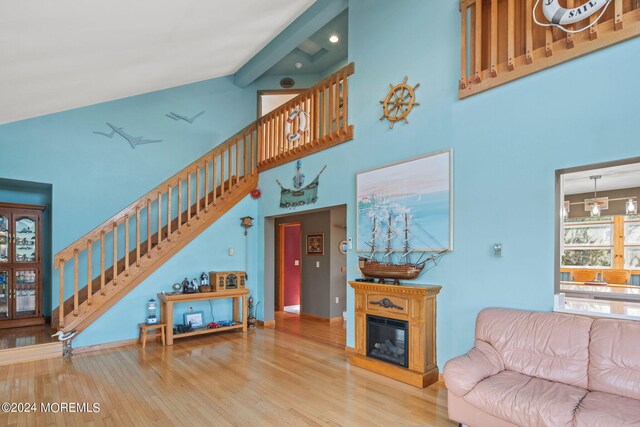 living room with high vaulted ceiling, light hardwood / wood-style floors, and beamed ceiling