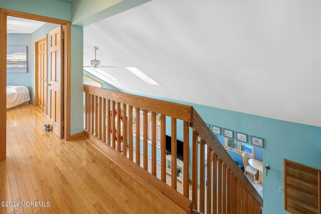 corridor featuring light wood-type flooring and vaulted ceiling with skylight