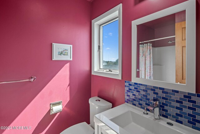 bathroom featuring decorative backsplash, a shower with curtain, vanity, and toilet