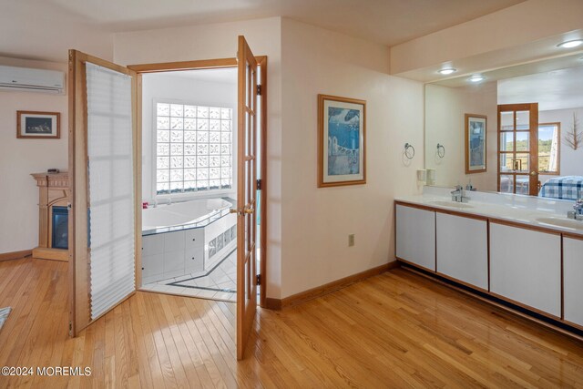 bathroom with vanity, hardwood / wood-style floors, a wall mounted air conditioner, and a tub