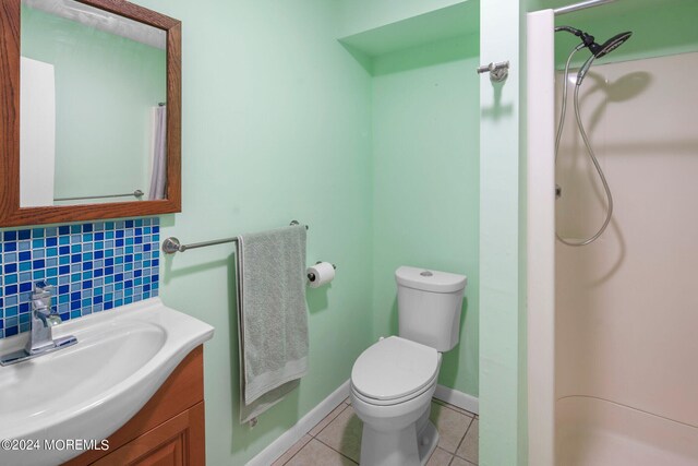 bathroom with decorative backsplash, a shower, vanity, toilet, and tile patterned floors