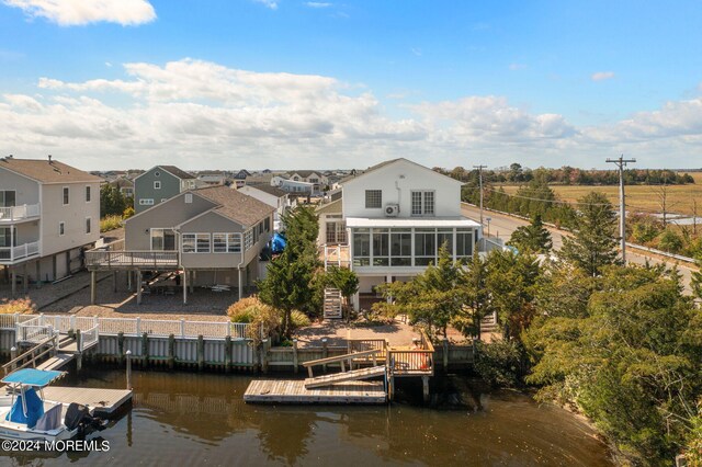 rear view of house with a sunroom and a deck with water view