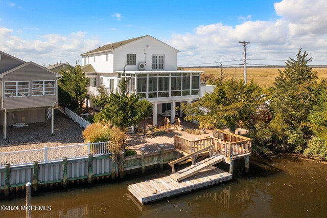 rear view of property with a sunroom and a deck with water view