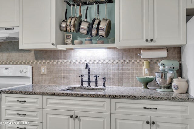 kitchen with backsplash, white cabinets, white range, and sink