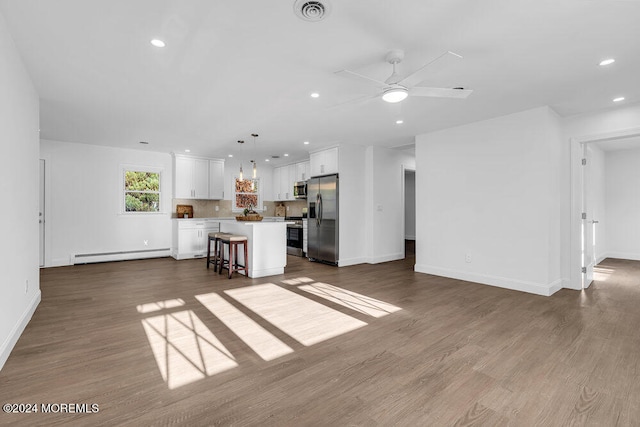 unfurnished living room with a baseboard radiator, hardwood / wood-style flooring, and ceiling fan