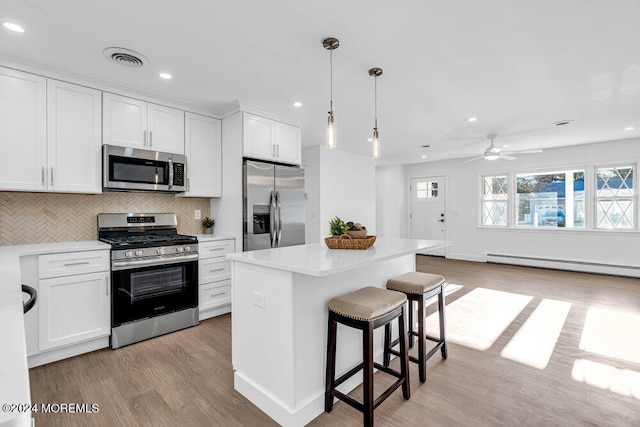 kitchen featuring white cabinetry, stainless steel appliances, light hardwood / wood-style flooring, pendant lighting, and a kitchen island