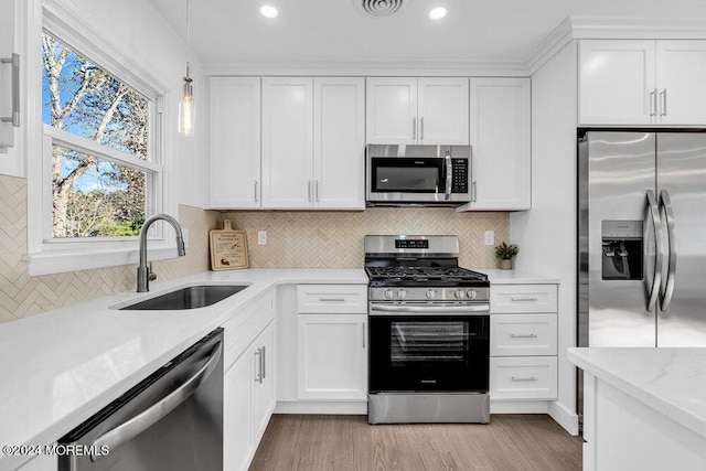 kitchen featuring white cabinetry, sink, pendant lighting, and appliances with stainless steel finishes