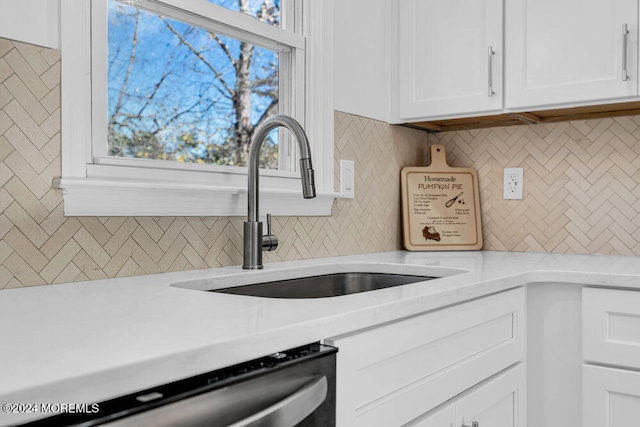 kitchen with backsplash, white cabinets, sink, stainless steel dishwasher, and light stone countertops