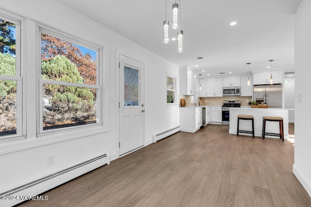 kitchen with white cabinetry, hanging light fixtures, appliances with stainless steel finishes, and a baseboard radiator