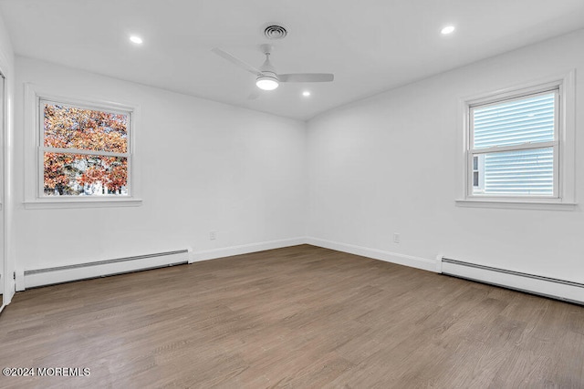 empty room featuring baseboard heating, ceiling fan, and hardwood / wood-style floors