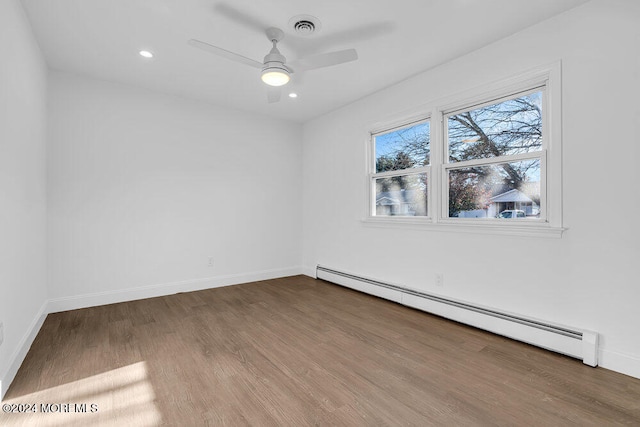 unfurnished room featuring hardwood / wood-style flooring, ceiling fan, and a baseboard heating unit