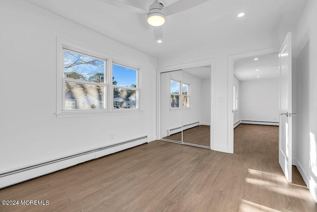 empty room with hardwood / wood-style floors, baseboard heating, and ceiling fan