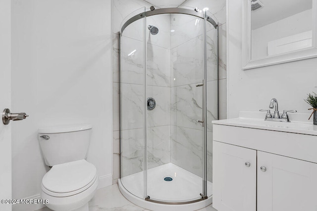 bathroom featuring a shower with door, vanity, and toilet