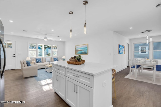 kitchen featuring ceiling fan, dark wood-type flooring, pendant lighting, white cabinetry, and a kitchen island